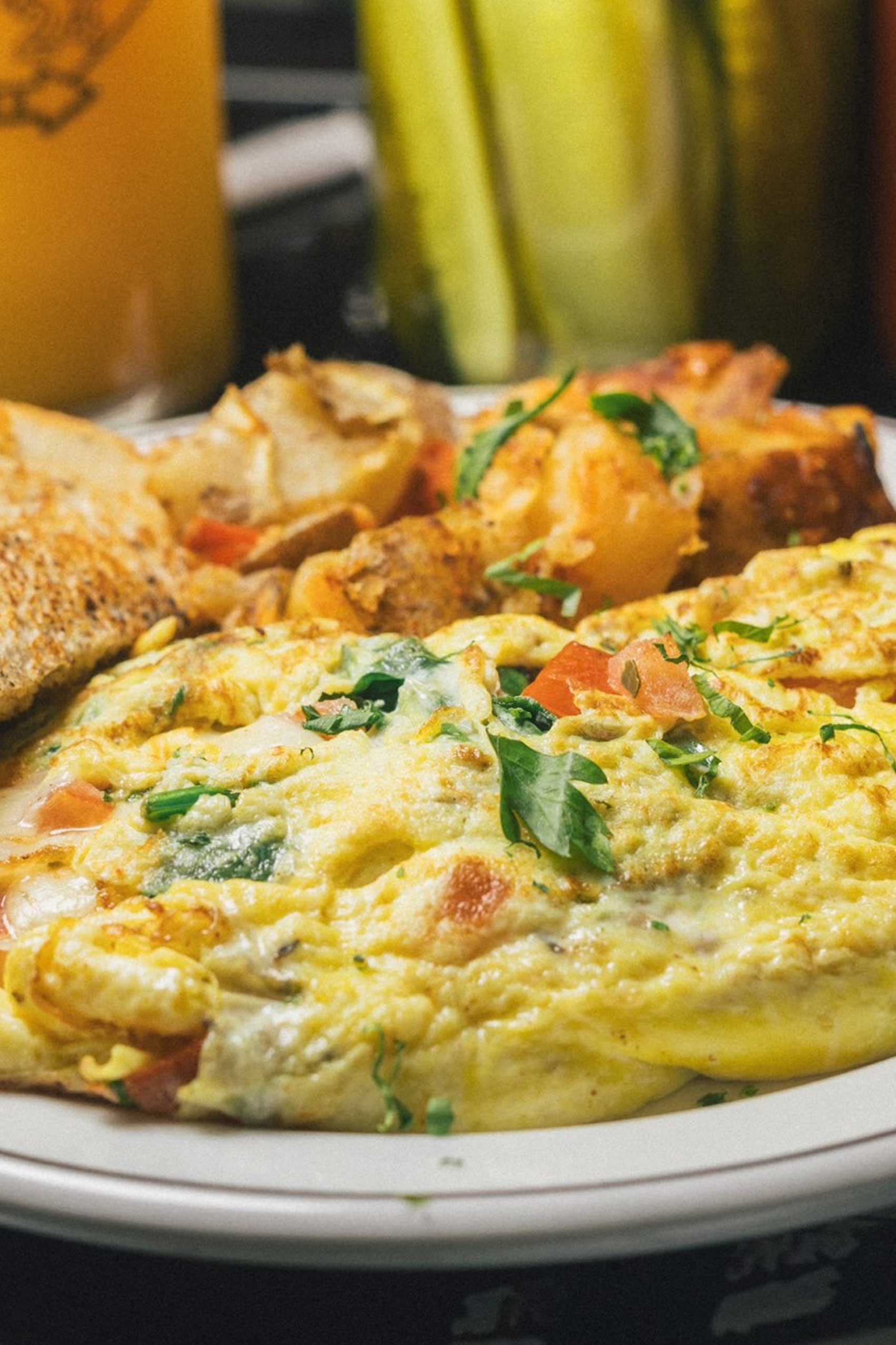 A classic breakfast plate from Diner 24 NYC featuring a fluffy, golden omelet packed with fresh vegetables and herbs, accompanied by crispy, seasoned home fries and toasted bread. This hearty dish is a perfect example of the high-quality diner food offered at this top-rated NYC diner. Located in Manhattan, Diner 24 NYC is celebrated as one of NYC’s favorite comfort food spots, delivering a balance of affordability and flavor. Open 24/7, it caters to those seeking the best 24-hour dining experience in NYC or a delicious, late-night meal in Manhattan. Known for being vegetarian-friendly, Diner 24 NYC also appeals to all breakfast enthusiasts with its extensive and inclusive menu.