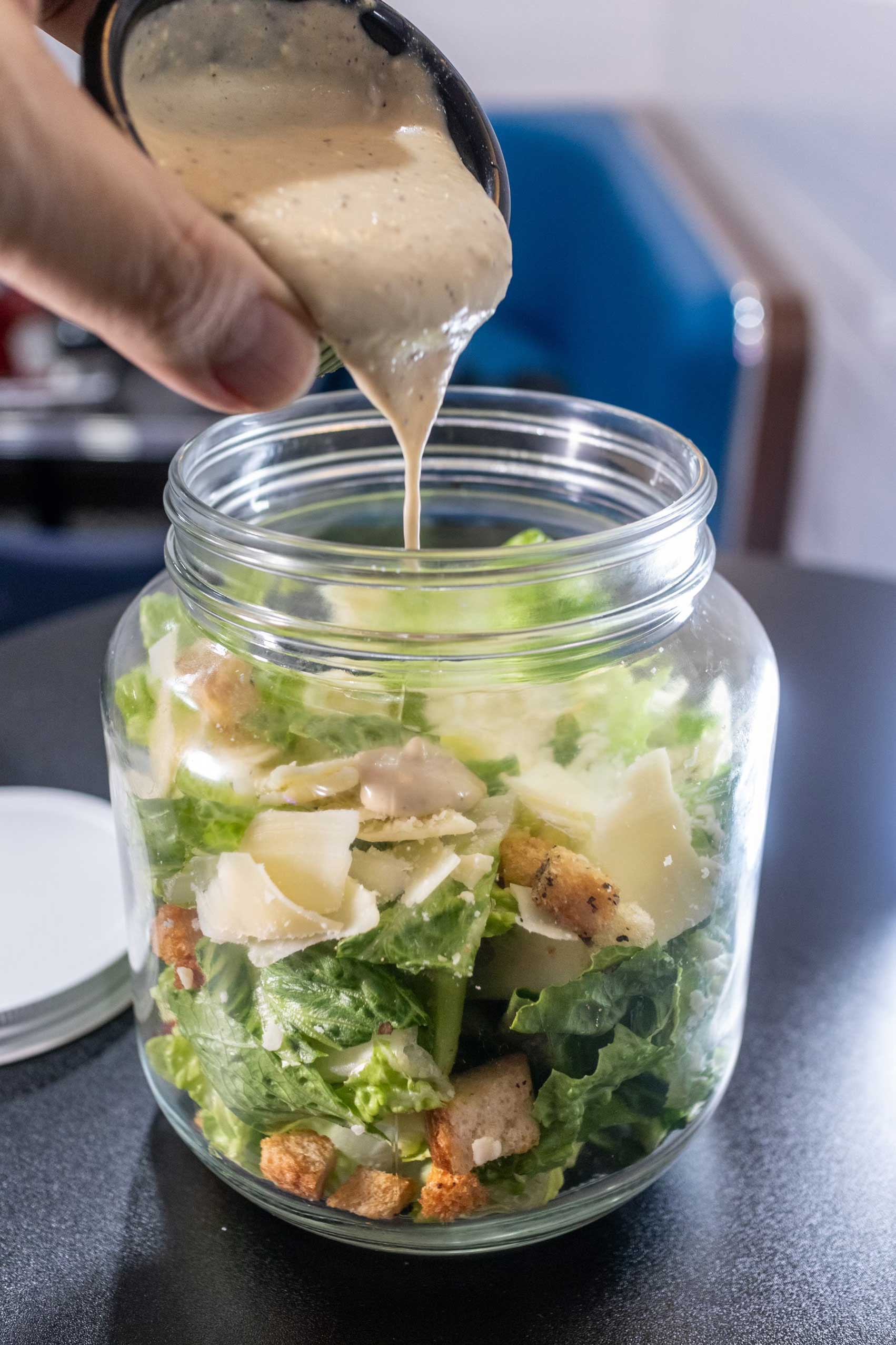 Fresh Caesar salad served in a jar at Diner 24 NYC, featuring crisp romaine lettuce, shaved Parmesan, crunchy croutons, and creamy Caesar dressing being drizzled to perfection. This innovative presentation offers a portable, eco-friendly twist on a classic dish, combining flavor and convenience. Whether you're dining at one of NYC’s top-rated diners or grabbing a quick bite from NYC’s favorite comfort food spots, this salad caters to those seeking high-quality diner food. A vegetarian-friendly option, it’s ideal for a light, refreshing meal at an affordable NYC comfort food destination.